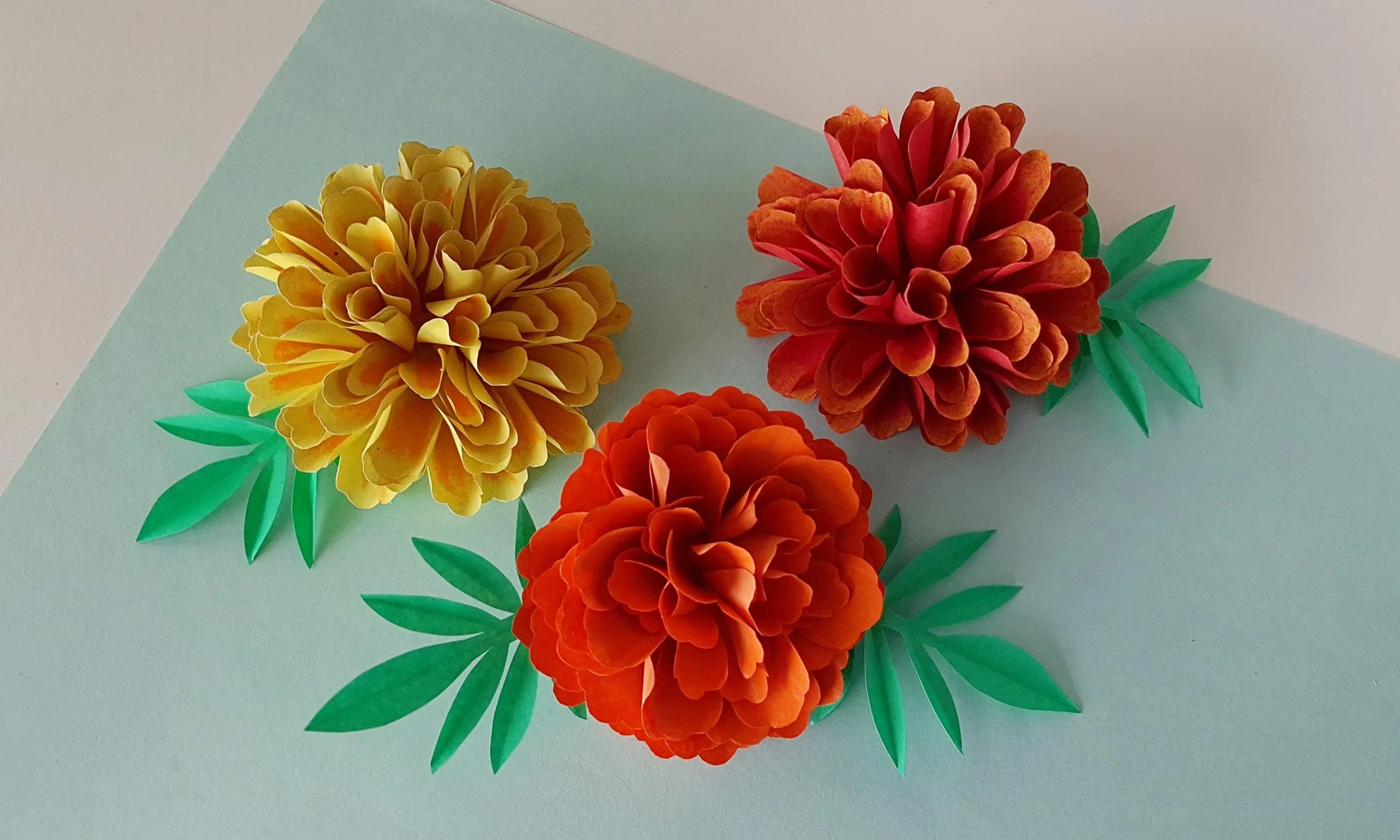 Finished realistic paper marigold flower craft displayed on a white background