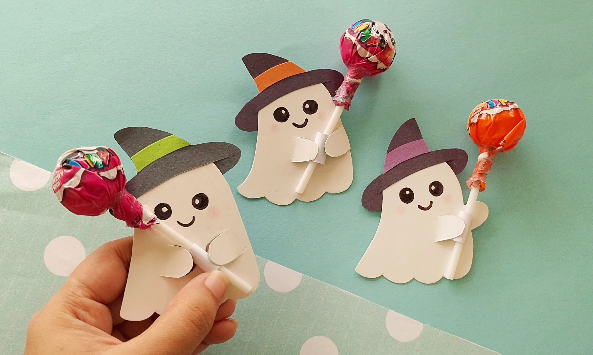Three finished ghost lollipop holders with witch hats Three paper ghost lollipop holders with witch hats, each holding a wrapped lollipop