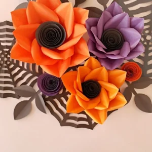 Halloween paper flower wall art with orange and purple flowers over black paper spider webs
