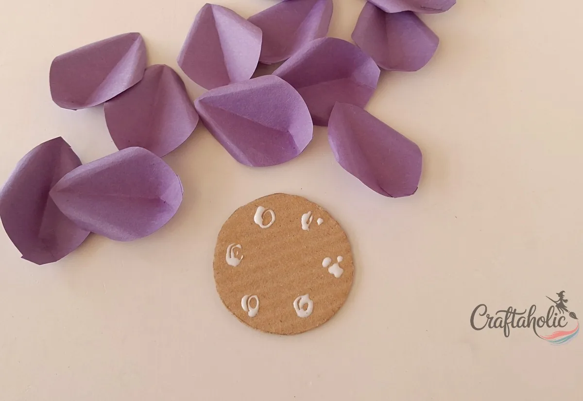 Applying glue around the side of the cardboard flower base