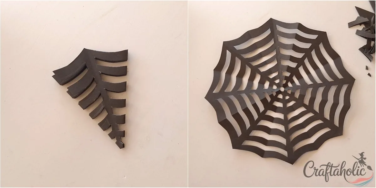 Unfolding the cut paper to reveal the spider web pattern