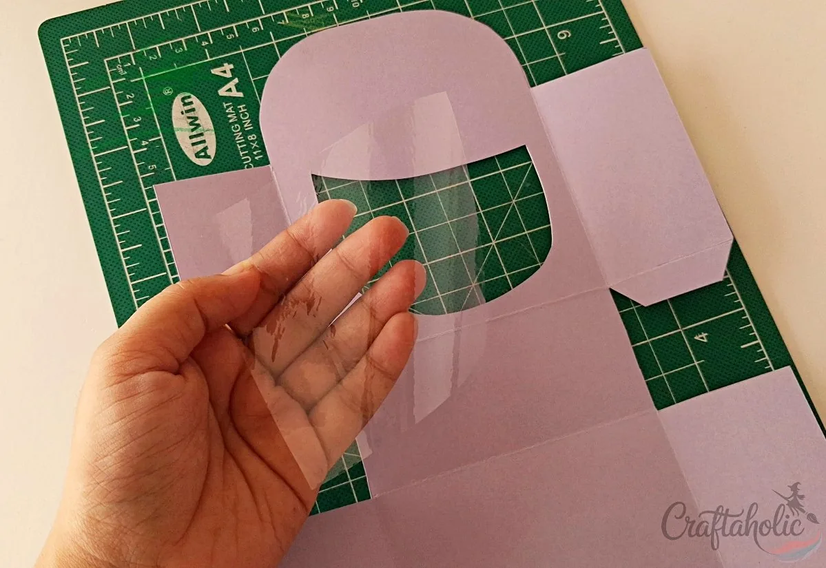 Covering the mouth cutout with a clear sheet on the monster snack box