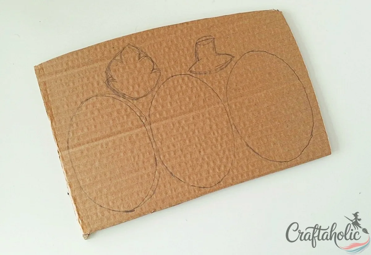 Tracing the pumpkin ovals, leaf and stem onto a cardboard sheet with a pencil