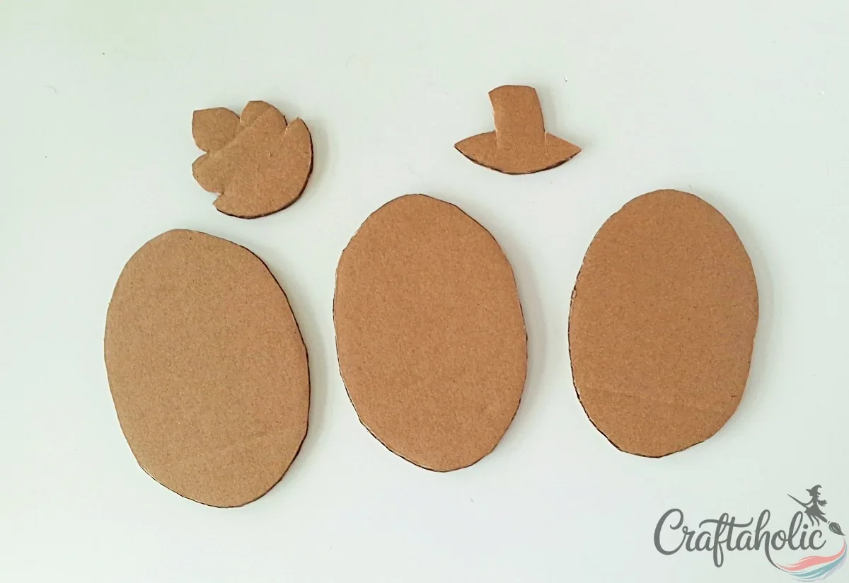 Three cardboard ovals, a leaf and a stem cut out for the cardboard pumpkin craft
