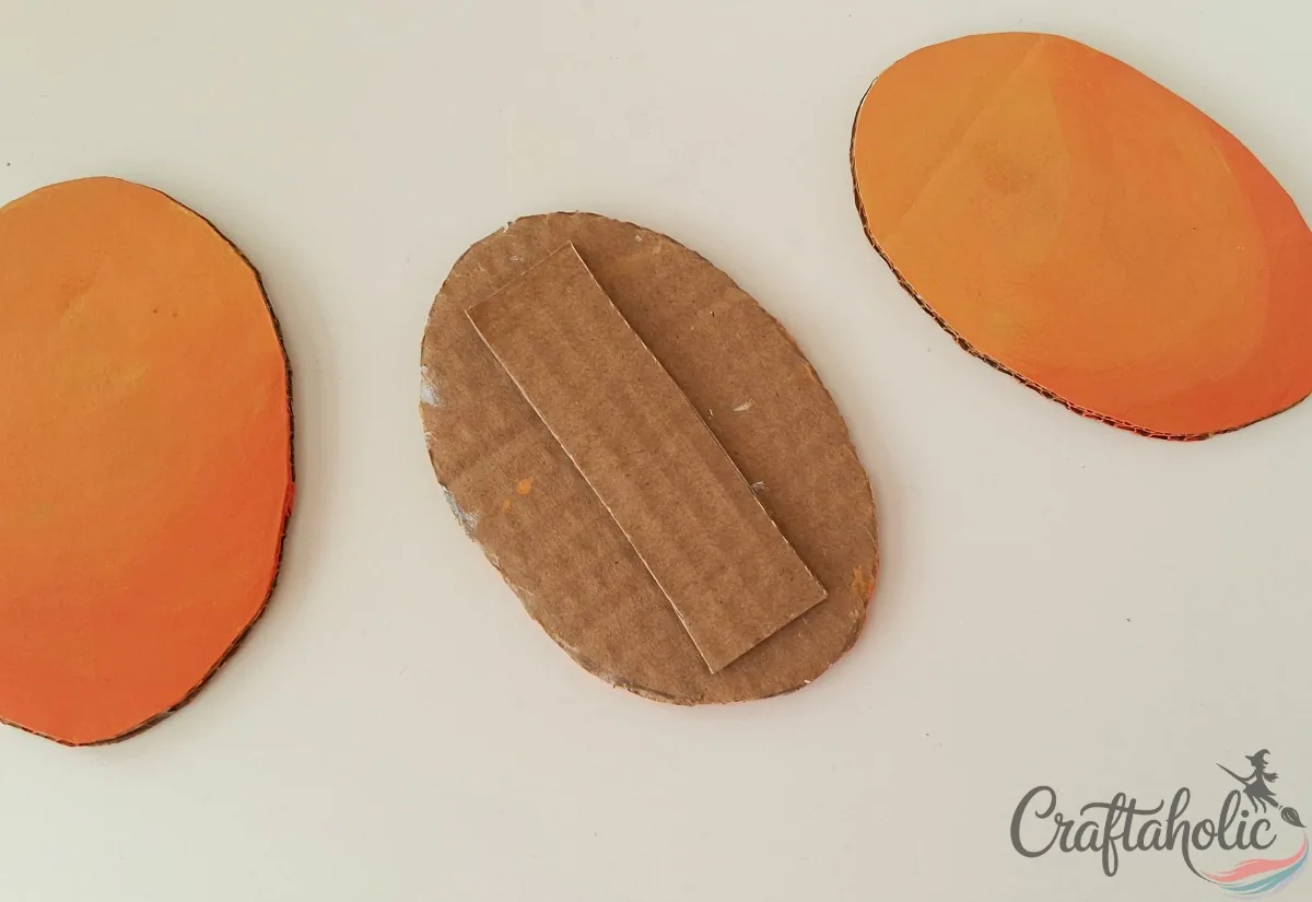 Cardboard back strip glued to the back of one painted pumpkin oval