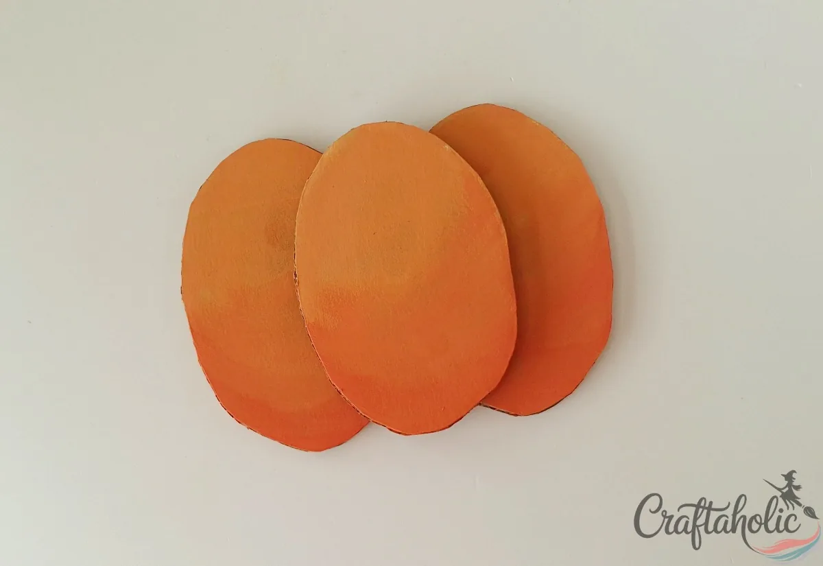 Strip oval glued over the seam of two plain ovals to form the pumpkin body