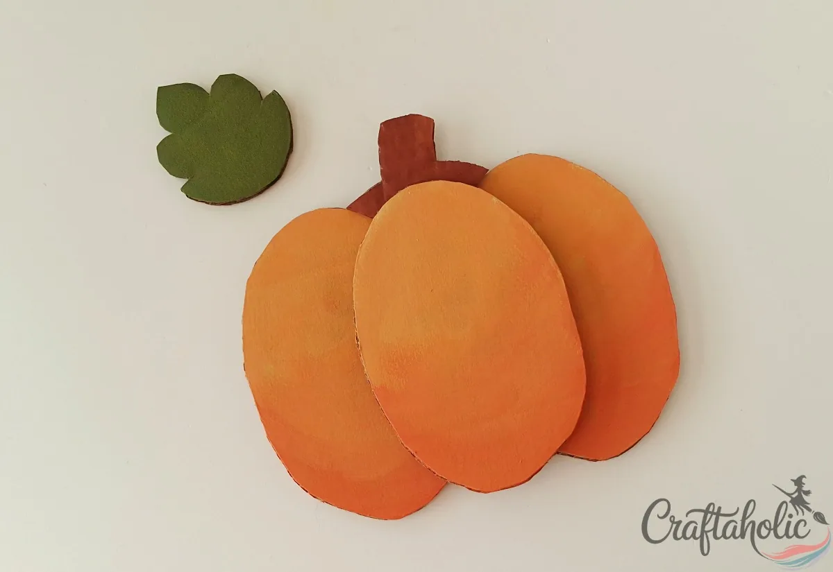 Brown cardboard stem glued behind the top of the cardboard pumpkin's middle oval