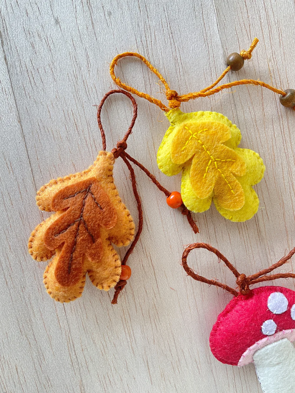Finished felt leaf ornament Finished yellow felt fall leaf ornament with a hanging loop and wooden beads