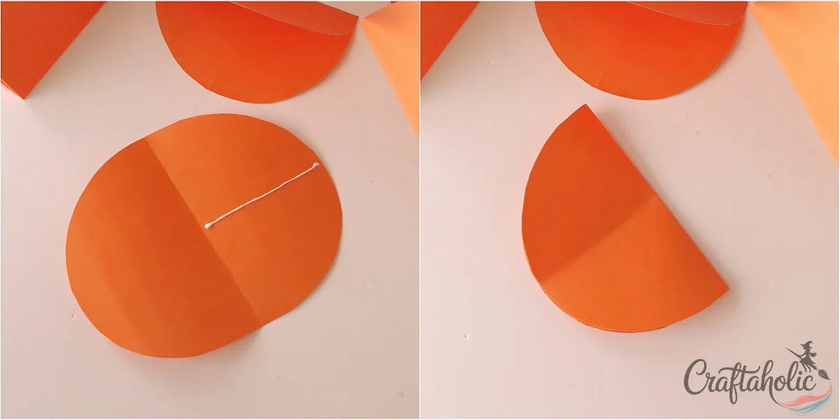 Gluing the middle line Unfolded orange paper piece with a line of glue across the middle beside a refolded half piece