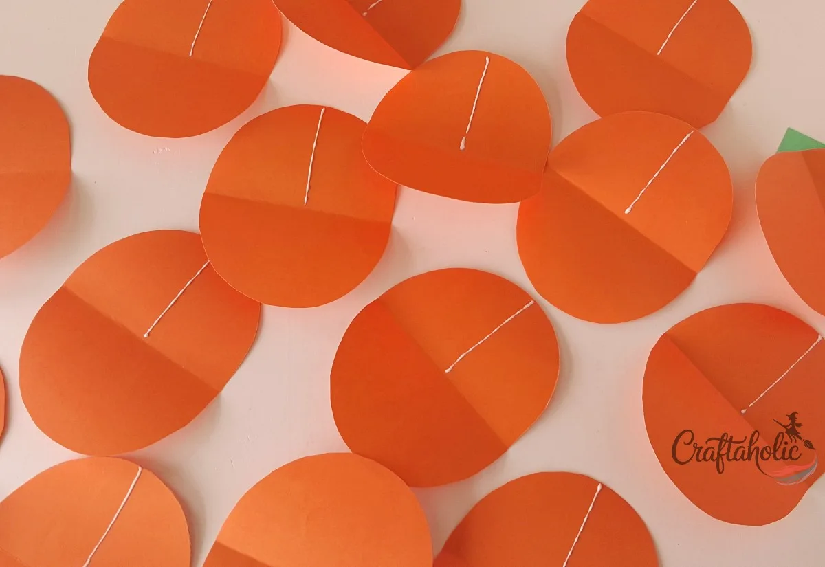 Batch gluing the pieces Unfolded orange paper pumpkin pieces laid out with a glue line on each one